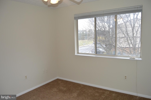 carpeted spare room featuring ceiling fan and plenty of natural light