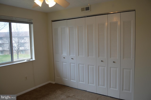 unfurnished bedroom with a textured ceiling, carpet floors, a closet, and ceiling fan