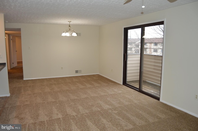 carpeted empty room featuring ceiling fan with notable chandelier and a textured ceiling