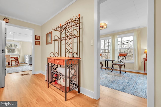 hall featuring hardwood / wood-style flooring, a healthy amount of sunlight, and crown molding