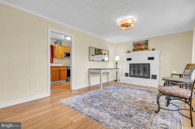 living room with crown molding, a fireplace, and light wood-type flooring