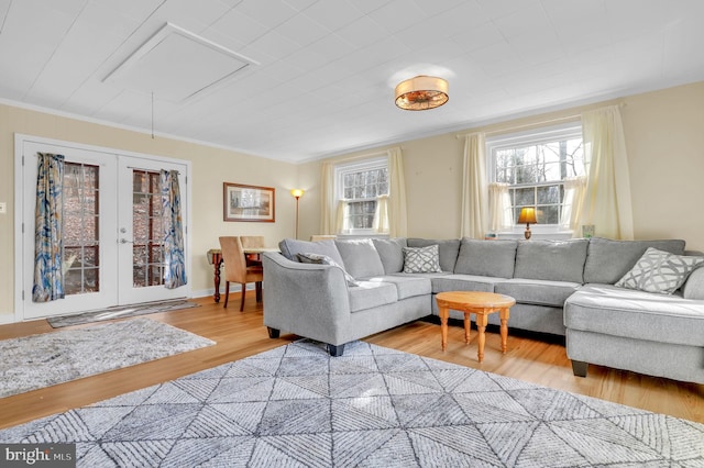 living room featuring light hardwood / wood-style floors, crown molding, and french doors