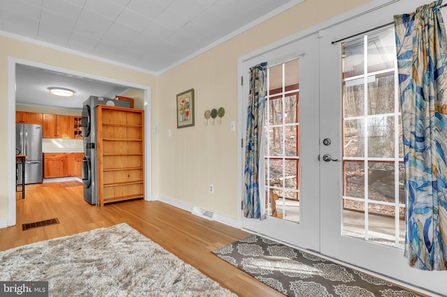 interior space with crown molding, light hardwood / wood-style flooring, and french doors