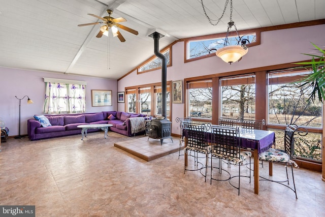 interior space featuring beamed ceiling, ceiling fan, a wood stove, and high vaulted ceiling