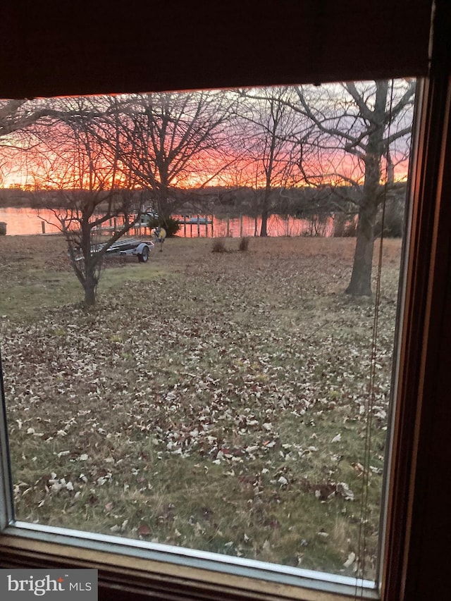 yard at dusk featuring a water view