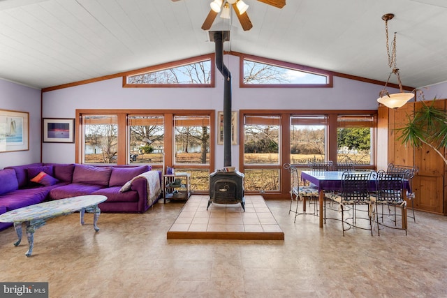 living room featuring beamed ceiling, a wood stove, plenty of natural light, and ceiling fan