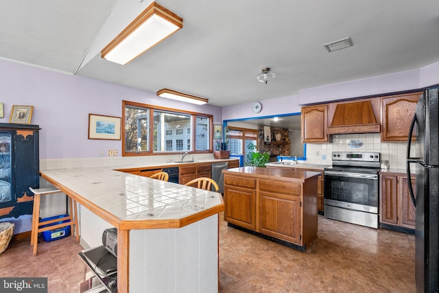 kitchen featuring tile countertops, custom exhaust hood, tasteful backsplash, a kitchen island, and stainless steel appliances