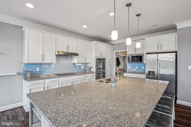 kitchen featuring stainless steel appliances, white cabinetry, and a center island with sink