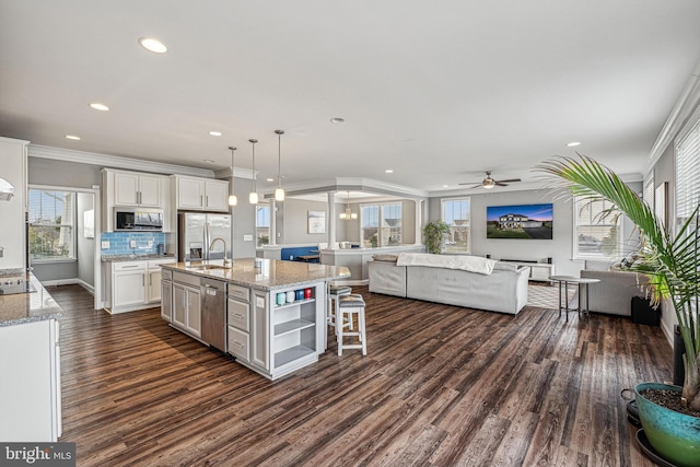 kitchen with a kitchen island with sink, sink, hanging light fixtures, white cabinetry, and stainless steel appliances