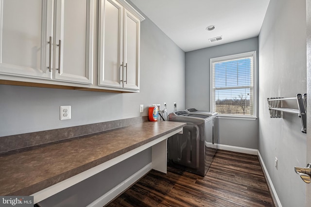 laundry room featuring dark hardwood / wood-style flooring, cabinets, and separate washer and dryer