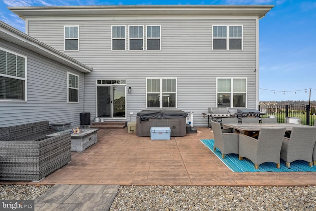 back of property featuring a hot tub, an outdoor fire pit, and a patio area