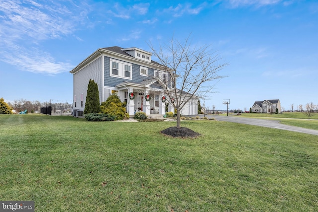 view of front of house featuring a porch, central AC unit, a front yard, and a garage