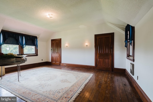 entryway featuring a textured ceiling, dark hardwood / wood-style floors, and lofted ceiling