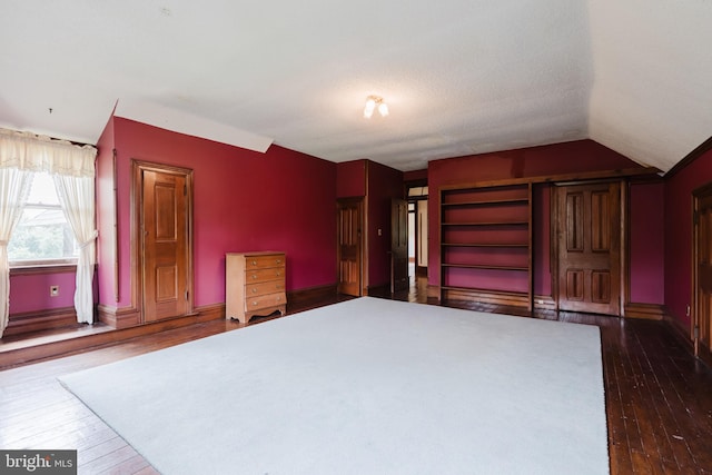 unfurnished bedroom with dark hardwood / wood-style flooring and lofted ceiling