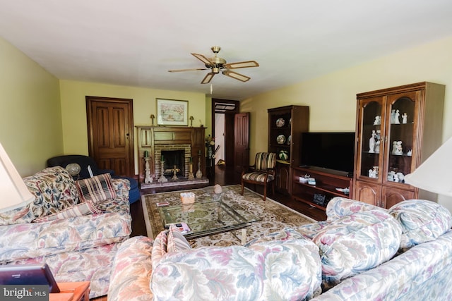 living room featuring hardwood / wood-style floors, ceiling fan, and a stone fireplace