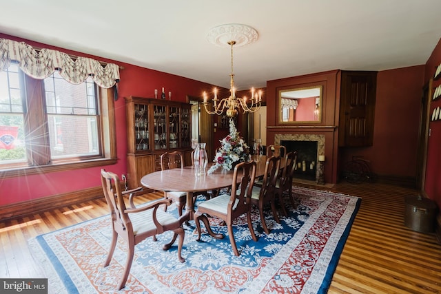 dining area featuring a fireplace, hardwood / wood-style floors, and a notable chandelier