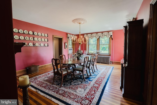 dining area with radiator, a chandelier, and hardwood / wood-style flooring