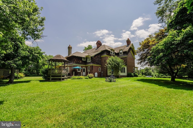 rear view of property with a gazebo and a lawn