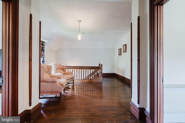 hallway with a textured ceiling, dark hardwood / wood-style flooring, and lofted ceiling