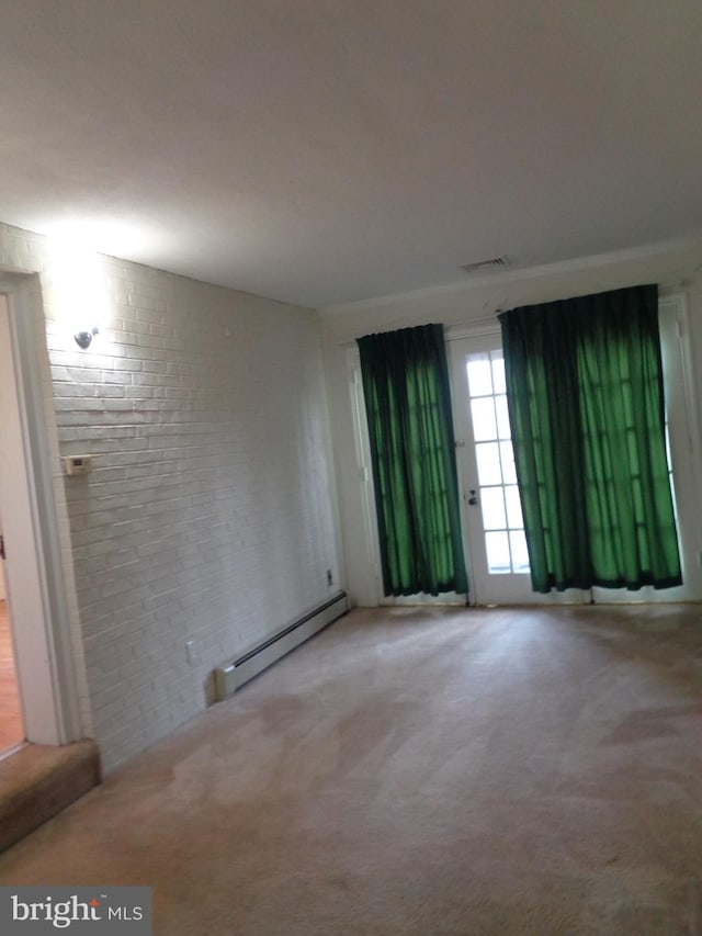 unfurnished room featuring carpet, brick wall, and a baseboard radiator