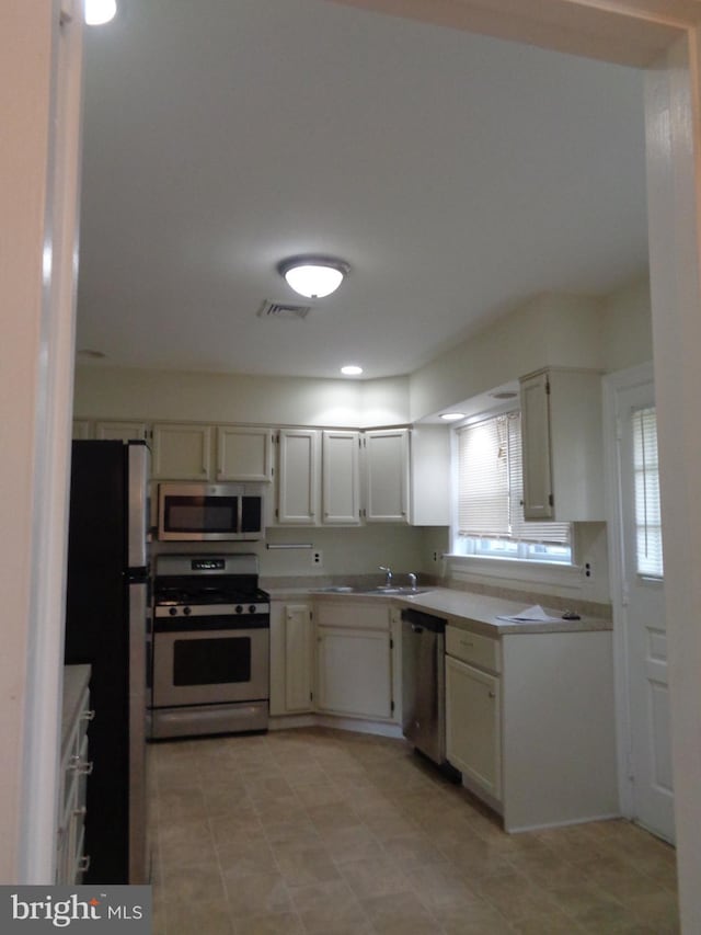 kitchen with sink, white cabinets, and appliances with stainless steel finishes