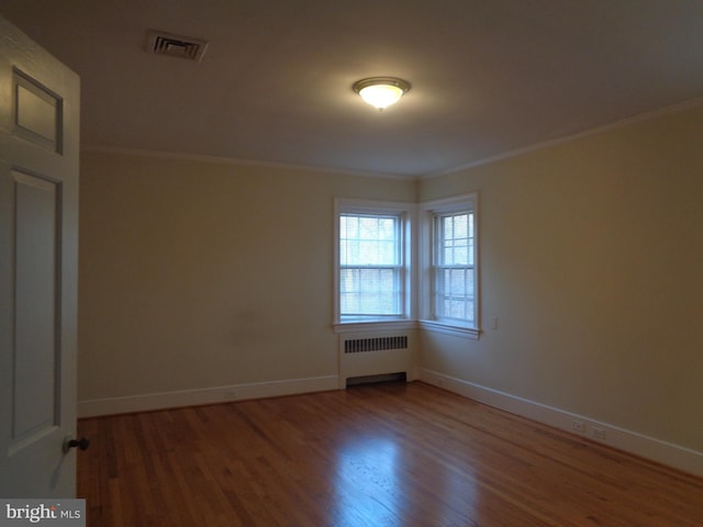 empty room with radiator, crown molding, and wood-type flooring