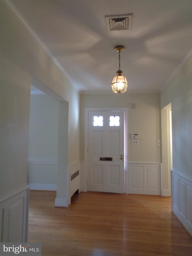 entryway with light wood-type flooring, radiator, and ornamental molding