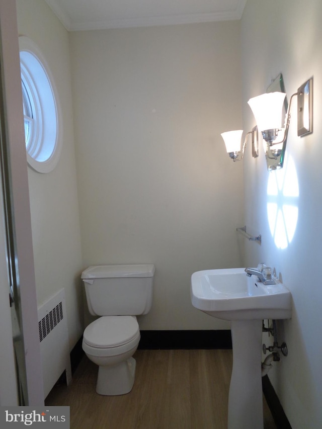 bathroom featuring hardwood / wood-style flooring, toilet, radiator heating unit, and ornamental molding