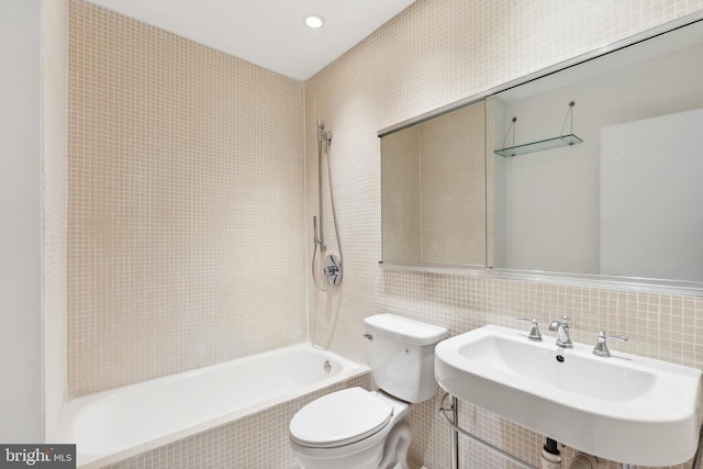 full bathroom with toilet, sink, tile walls, and tiled shower / bath