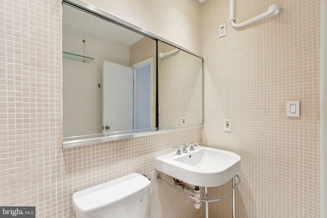 bathroom featuring toilet, tile walls, and sink