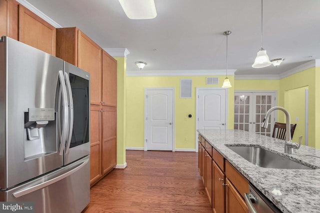 kitchen with sink, light stone counters, crown molding, pendant lighting, and appliances with stainless steel finishes