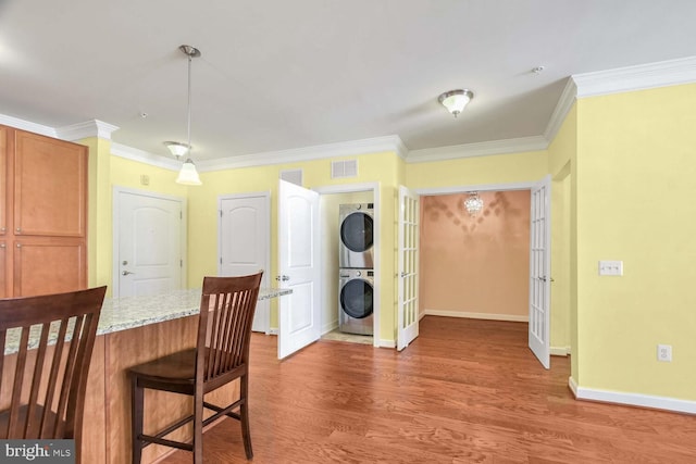 dining room featuring ornamental molding, dark hardwood / wood-style floors, and stacked washer and clothes dryer