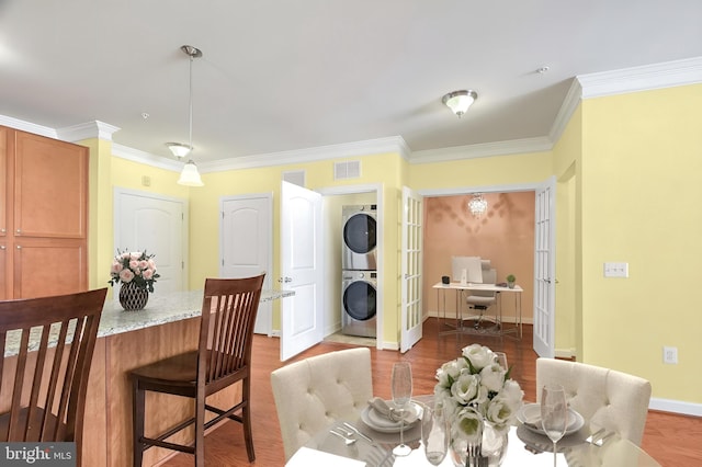 dining room featuring stacked washer and dryer, dark hardwood / wood-style floors, and ornamental molding