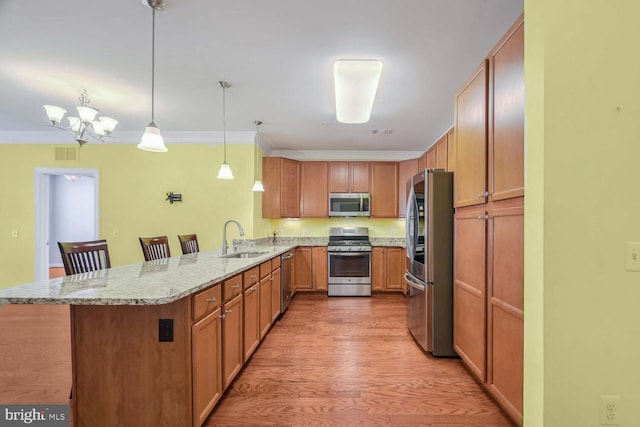 kitchen with pendant lighting, a breakfast bar, sink, appliances with stainless steel finishes, and kitchen peninsula