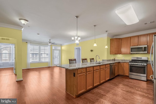 kitchen featuring sink, stainless steel appliances, kitchen peninsula, crown molding, and pendant lighting