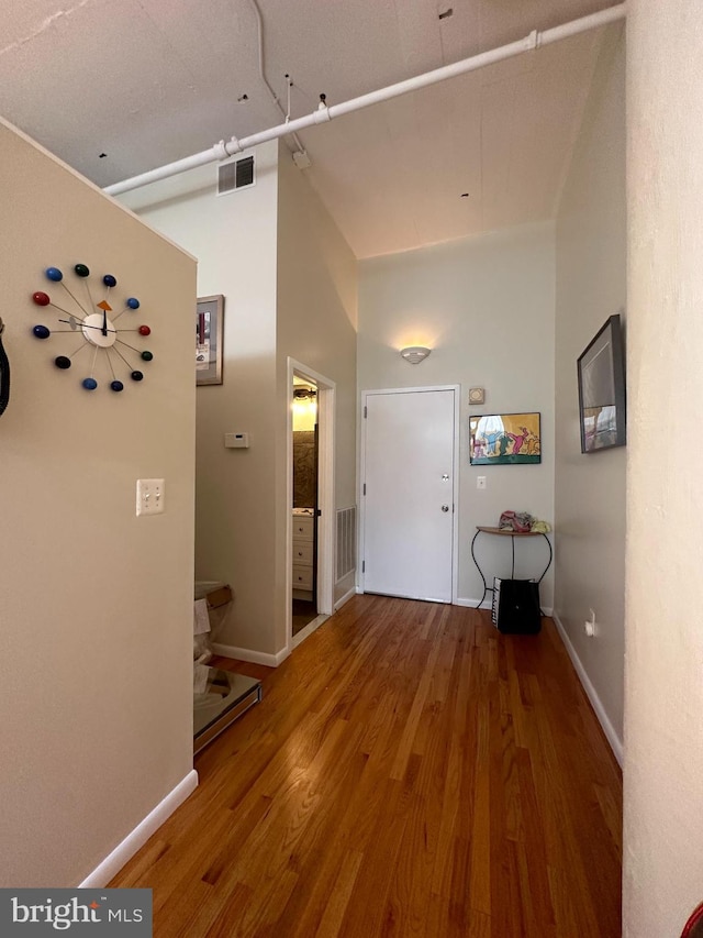 corridor featuring hardwood / wood-style floors and high vaulted ceiling