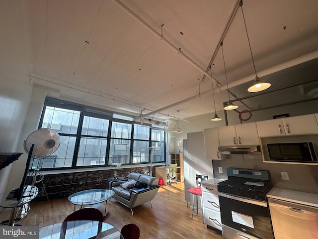 kitchen with white cabinets, light wood-type flooring, stainless steel appliances, and hanging light fixtures