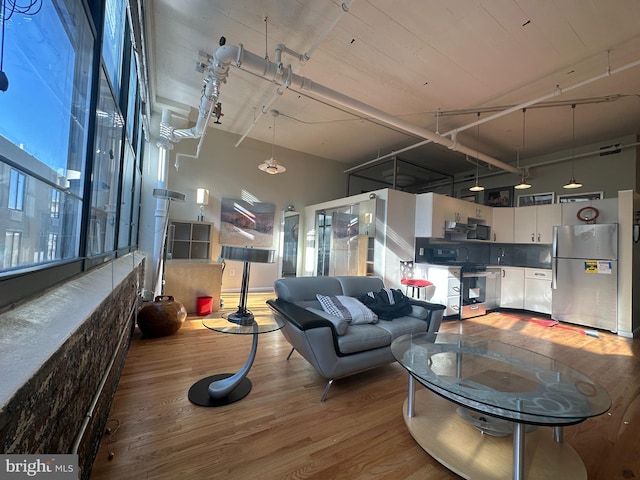 living room with plenty of natural light, wood-type flooring, and a towering ceiling