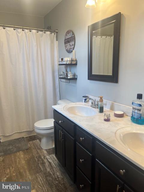 bathroom with hardwood / wood-style floors, vanity, a shower with shower curtain, and toilet