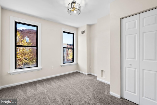 unfurnished bedroom with carpet flooring, an inviting chandelier, and a closet