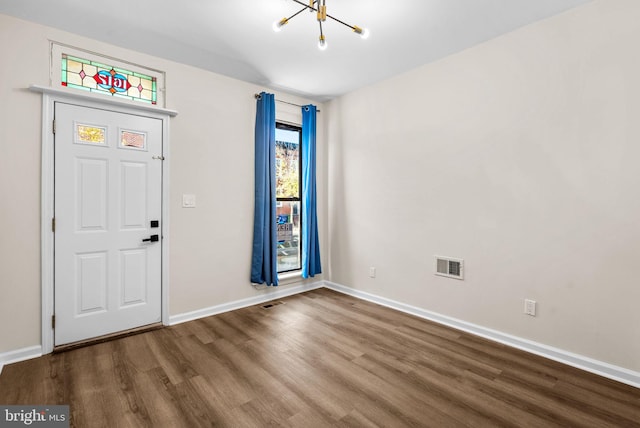 entryway with wood-type flooring and a notable chandelier