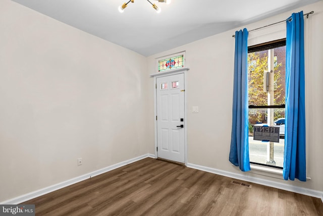 interior space featuring a notable chandelier, a healthy amount of sunlight, and dark hardwood / wood-style flooring