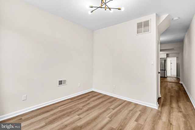 unfurnished room with light hardwood / wood-style flooring and a chandelier