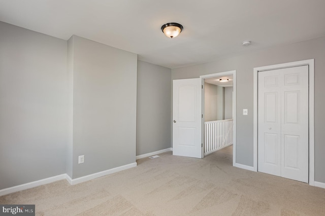 unfurnished bedroom featuring a closet and light colored carpet