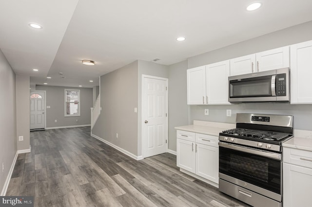 kitchen with white cabinets, light stone countertops, stainless steel appliances, and hardwood / wood-style flooring