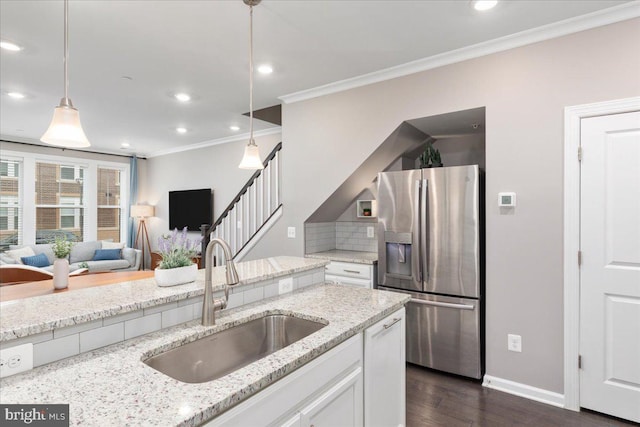 kitchen with sink, light stone countertops, stainless steel refrigerator with ice dispenser, and hanging light fixtures