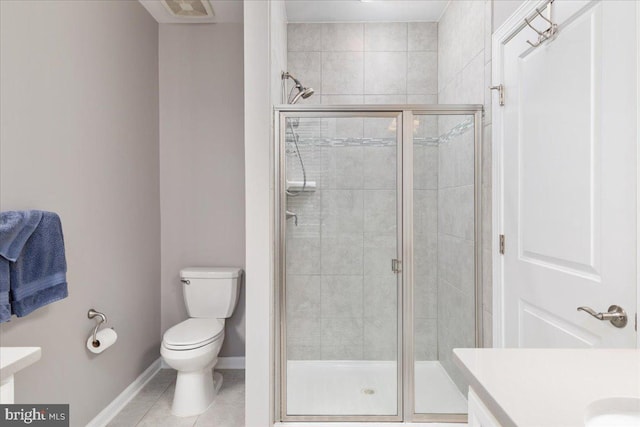 bathroom with tile patterned flooring, vanity, a shower with shower door, and toilet