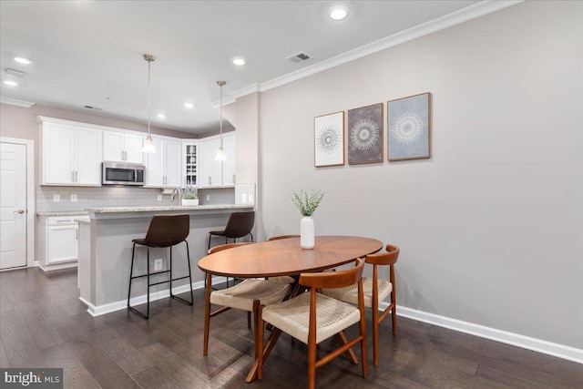 dining area featuring crown molding, dark hardwood / wood-style flooring, and sink