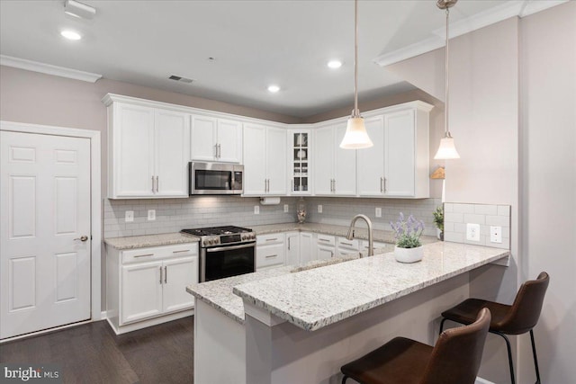 kitchen with white cabinets, appliances with stainless steel finishes, and pendant lighting