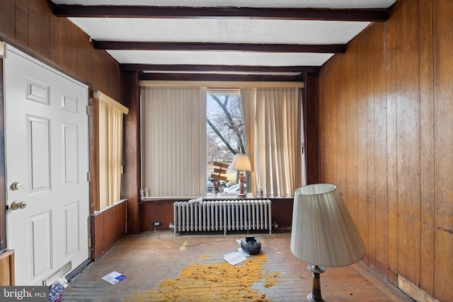 miscellaneous room with wood walls, radiator heating unit, beamed ceiling, and wood-type flooring